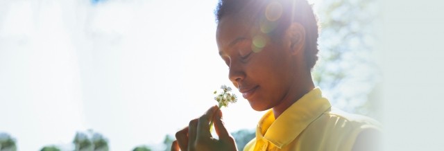 Young woman smells a flower in the sunlight