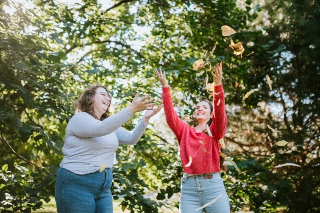 Two young women are throwing leaves in the air